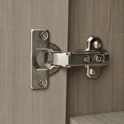 Acercamiento a bisagra metálica bidimensional de alta resistencia instalada en puerta de gabinete color ceniza.